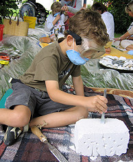 Foto: In einer Gruppe von Kindern bettigt sich ein kleiner Junge mit einem Gasbetonstein spielerisch als 'Bildhauer'.